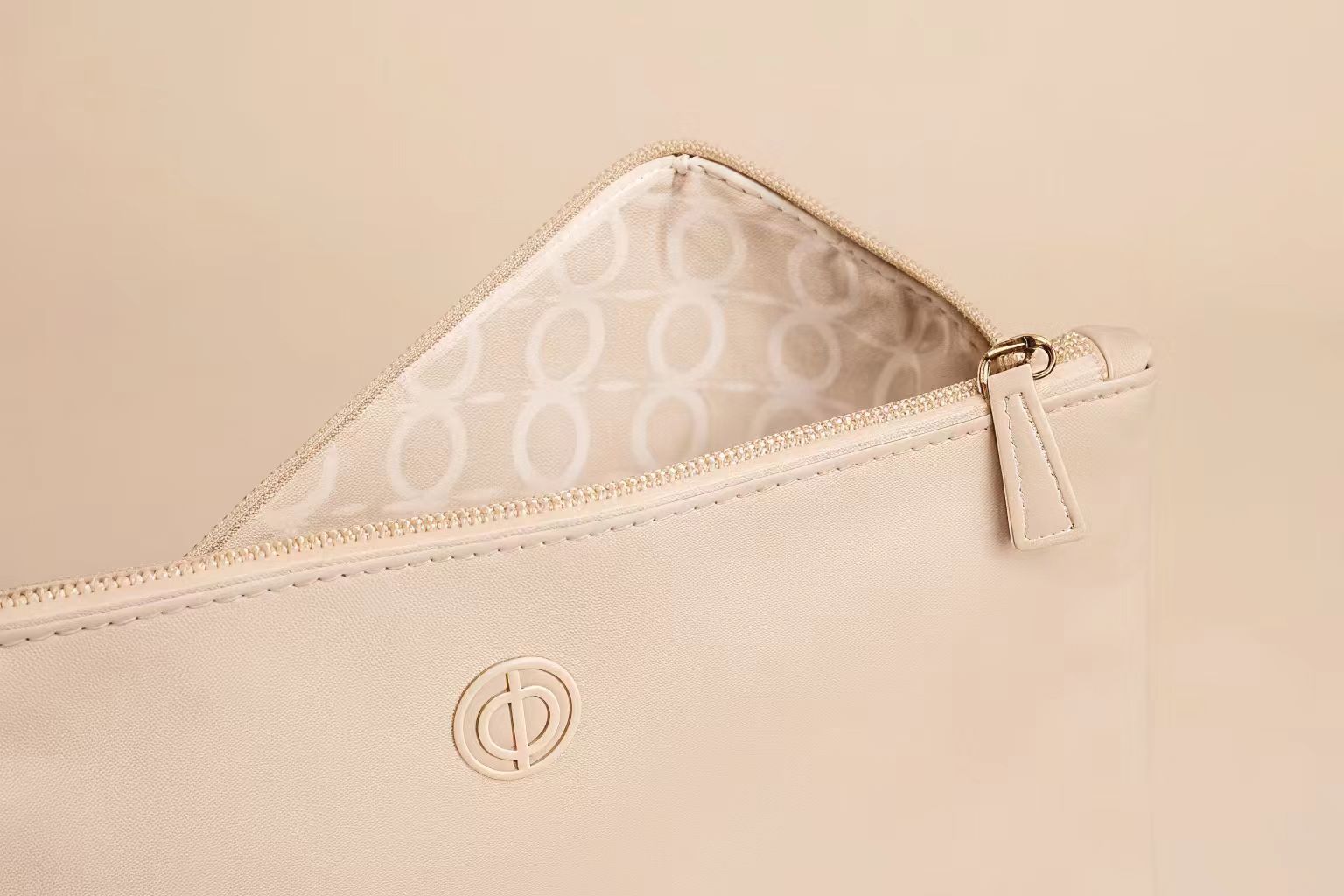 Branding Details for Custom Makeup Bags A close-up of a custom makeup bag showing a debossed logo, a custom zipper pull, and a patterned interior lining